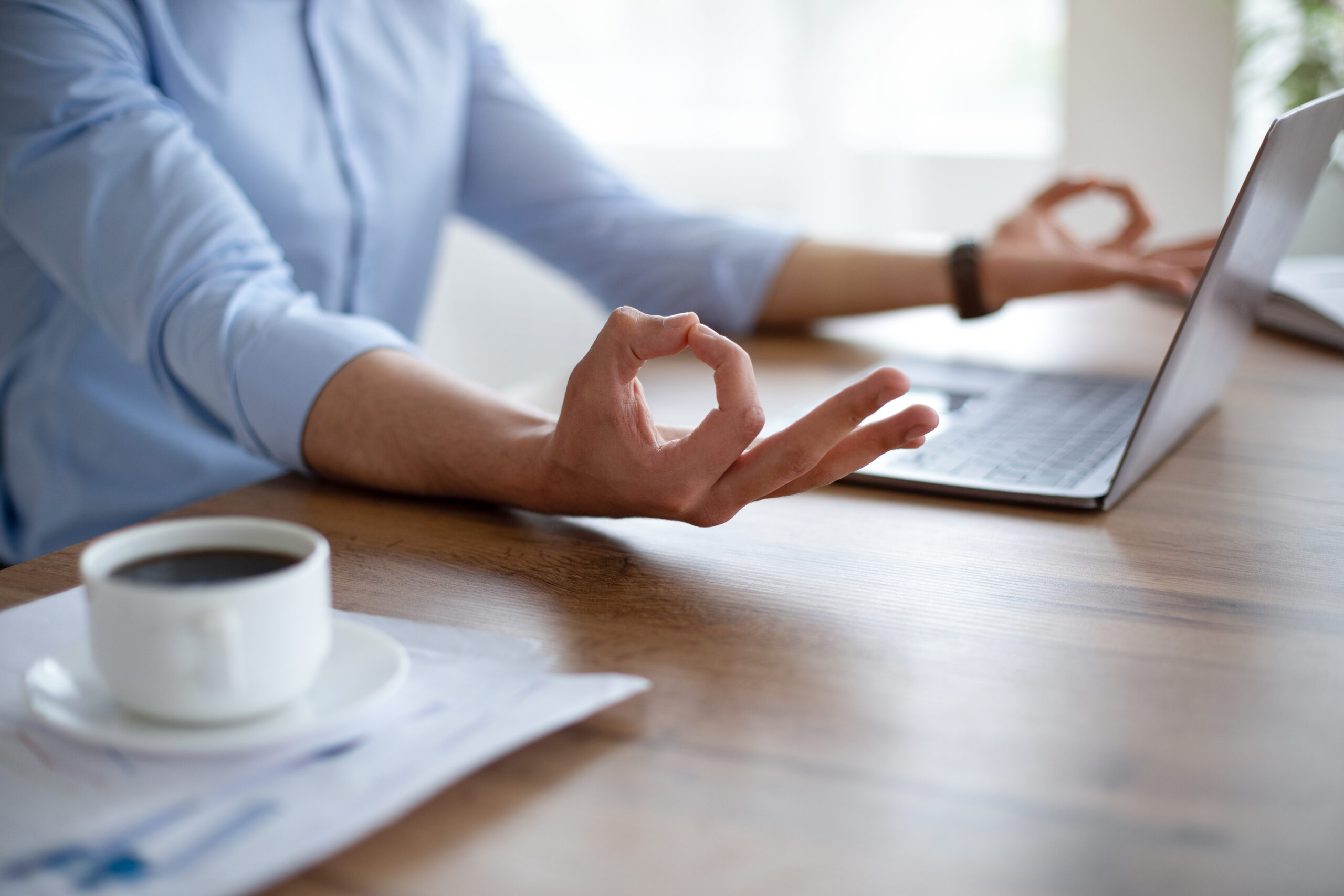 Unrecognizable Arab guy meditating in front of laptop pc, making gyan mudra, trying to keep calm at workplace